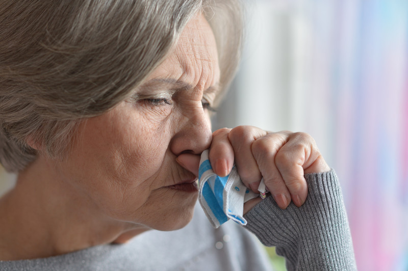 Senior woman holding hand to mouth seemingly coughing | Pneumonia and Seniors | Comfort Keepers Vancouver | BLOG POST