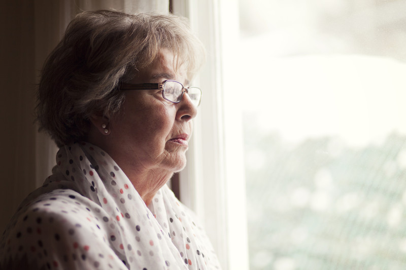 Senior looking out window | Senior Loneliness and Depression | BLOG POST | Comfort Keepers Victoria