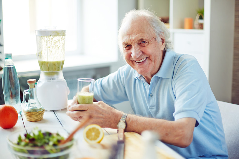 Senior male eating in kitchen and smiling at camera | Healthy Senior Diet | BLOG POST | Comfort Keepers Victoria